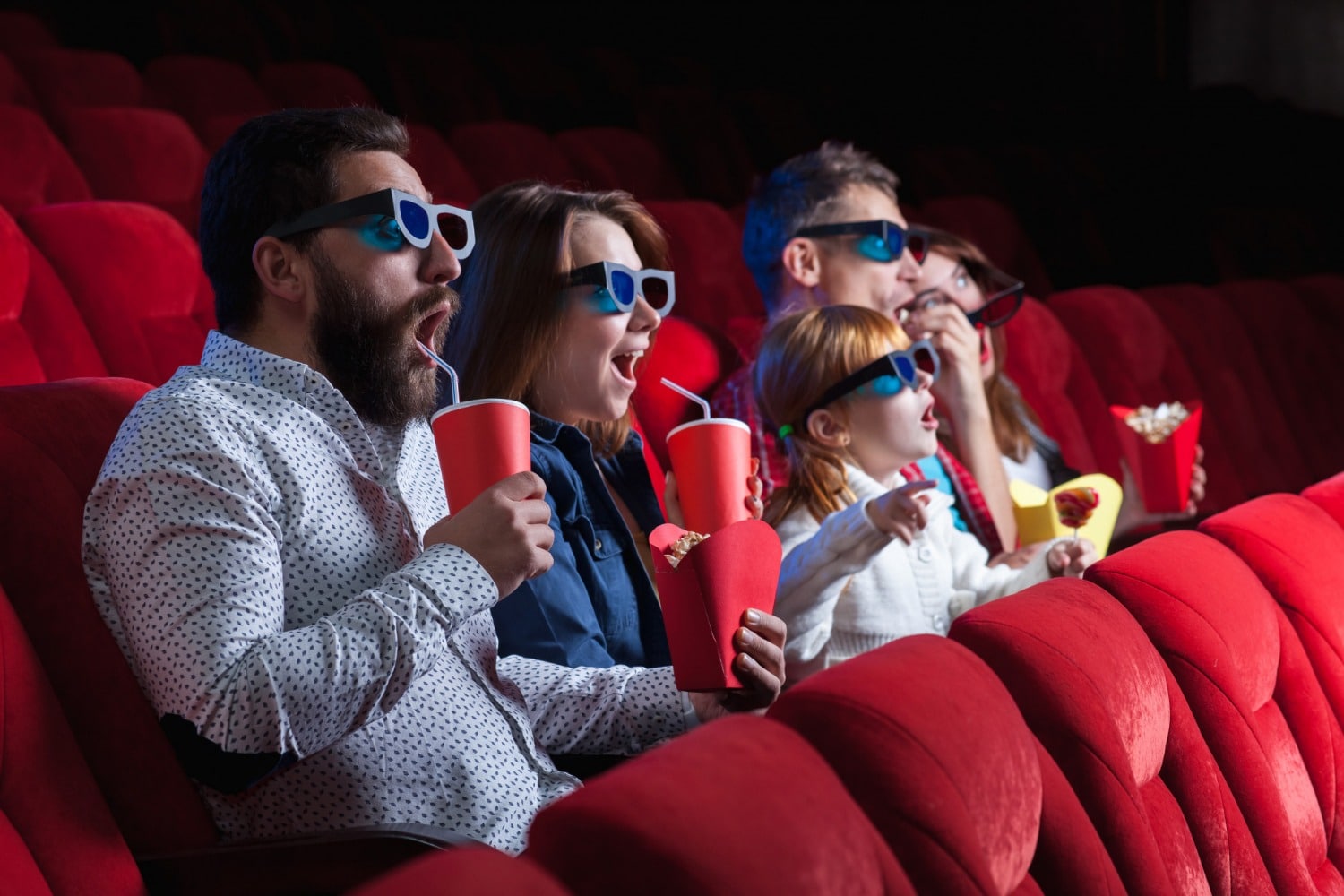 Des spectateurs assis sur les sièges rouges d'un cinéma