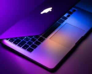 Un MacBook rétroéclairé en violet est posé sur une table