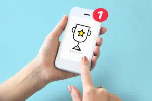 un smartphone en gros plan avec en fond d’écran le logo d'un trophée