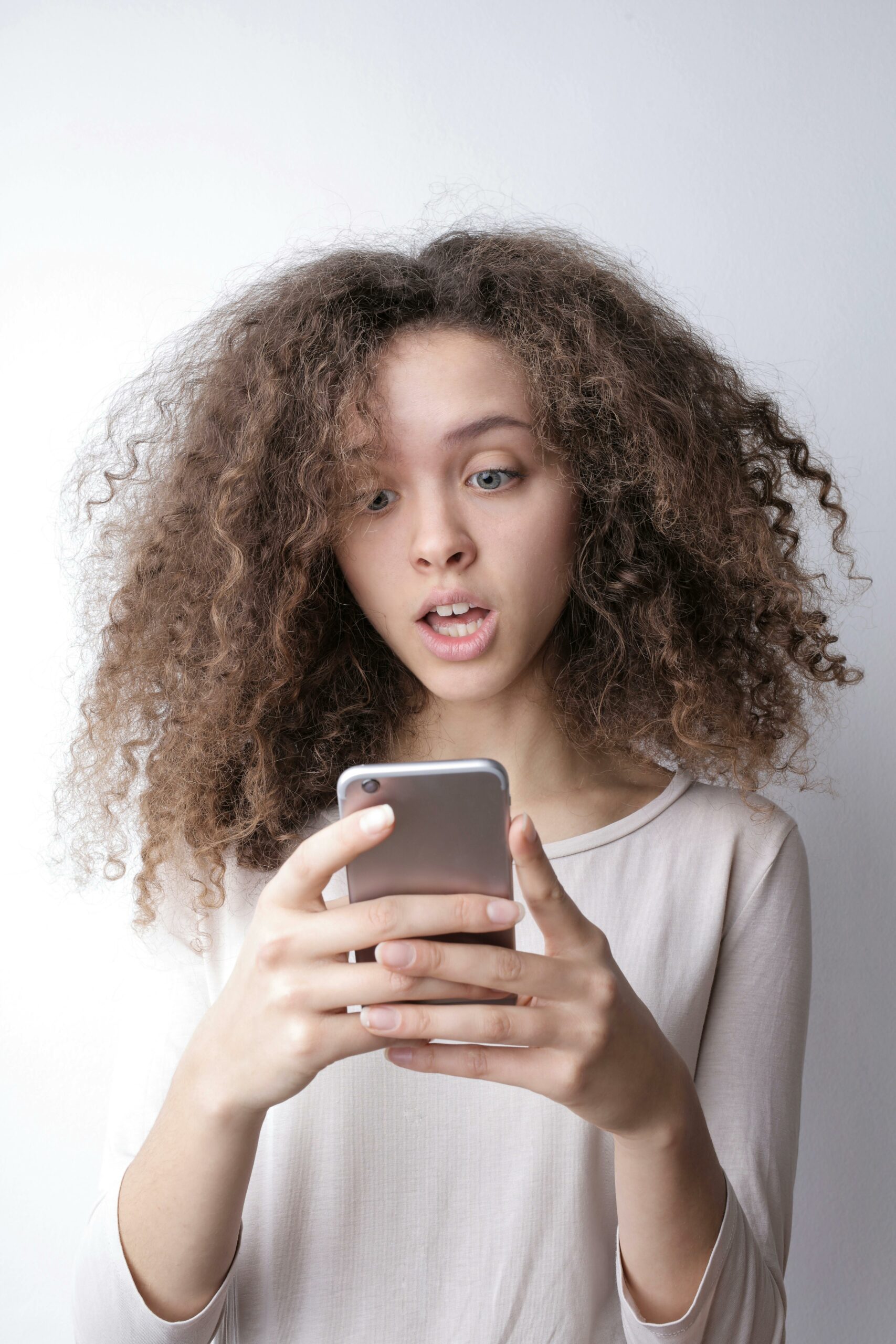 une femme devant son smartphone représentant les différentes arnaques par SMS