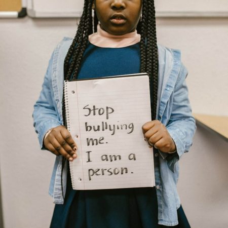 une enfant tient un papier avec marqué stop au harcèlement