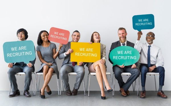 des personnes assises sur un banc tiennent des pancartes avec écrit embauche carriere emploi